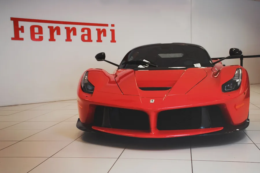 Red Ferrari LaFerrari on a white tiled showroom floor beneath the Ferrari wordmark